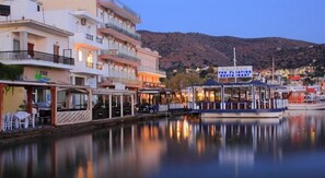 A waterfront hotel with multiple balconies and a restaurant named "The Floating Restaurant" docked at the pier. - Aristea Hotel (Agios Nikolaos)