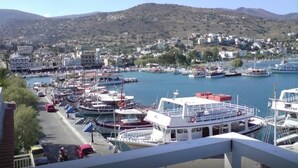 A marina with boats docked, a road with vehicles, and buildings in the background. - Aristea Hotel (Agios Nikolaos)