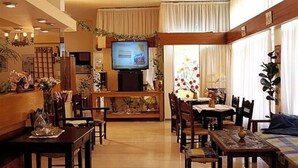 Um saguão de hotel com televisão, área de refeições e assentos.