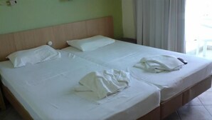 Uma cama de casal com lençóis brancos, cabeceira de madeira e uma pequena mesa de cabeceira com abajur.