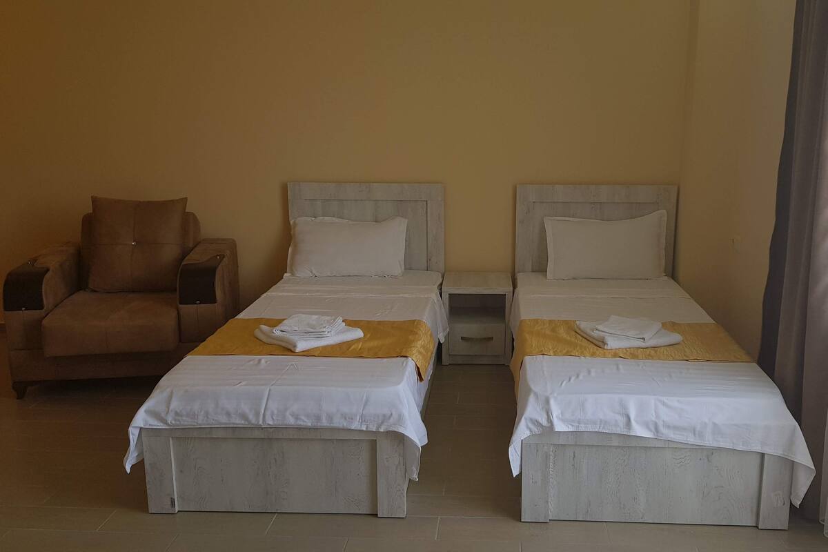 A hotel room with two beds, a sofa, and a nightstand.