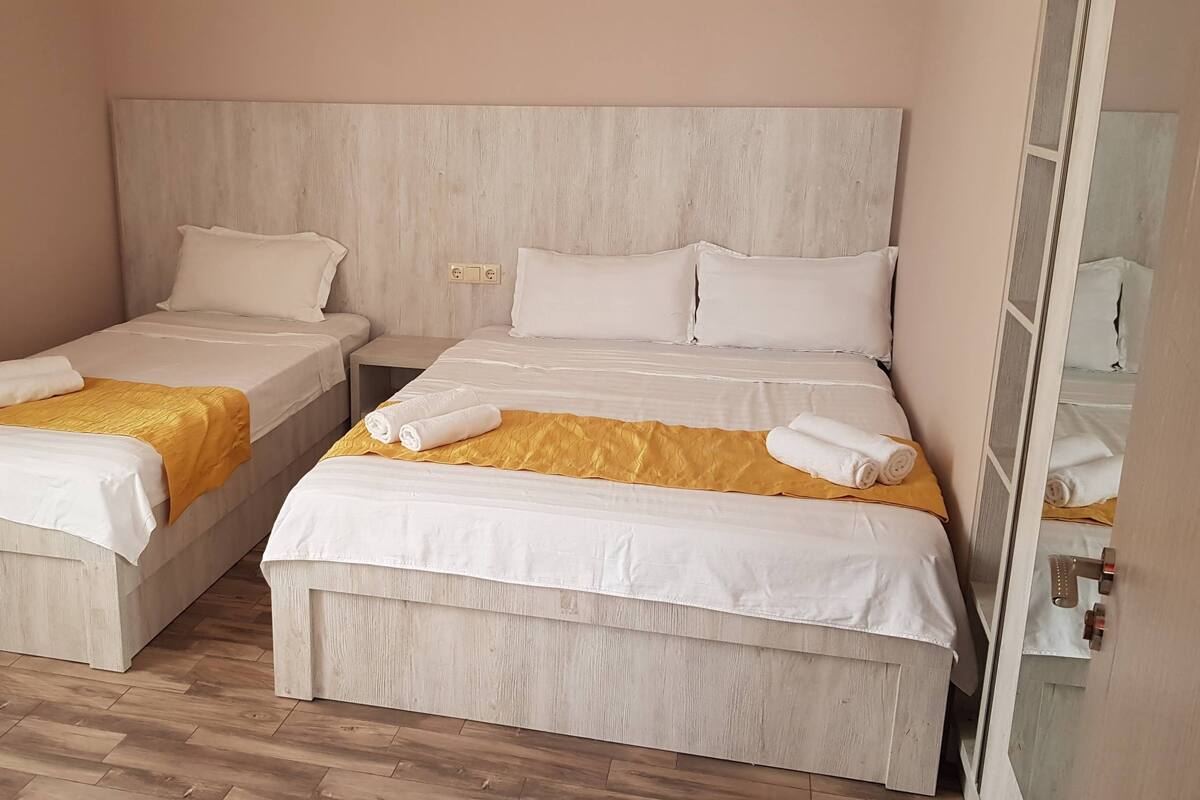 Two single beds with wooden headboards, white bedding, and yellow throw blankets.