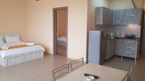 A compact hotel room with a bed, a small kitchenette, and a dining area. - Nakashidzes Apartments (Batumi)