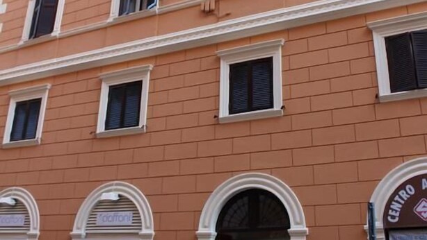 Ein mehrgeschossiges Gebäude mit Rundbogenfenstern und einem Schild, auf dem "CENTRO A" steht.