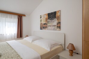 A bedroom with a bed, two bedside lamps, a window with sheer curtains, and a wall-mounted artwork. - Apartment Tara Apt 3 (Medulin)