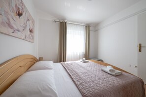 A hotel room with a bed, a bedside lamp, a painting on the wall, and a window with curtains.