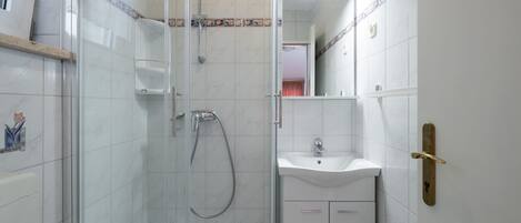 A bathroom with a glass-enclosed shower, a sink, and a mirror.