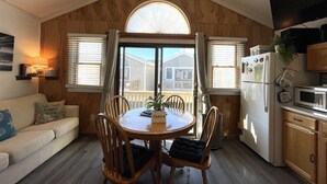 A cozy kitchen with a dining table, wooden chairs, a refrigerator, and a microwave.