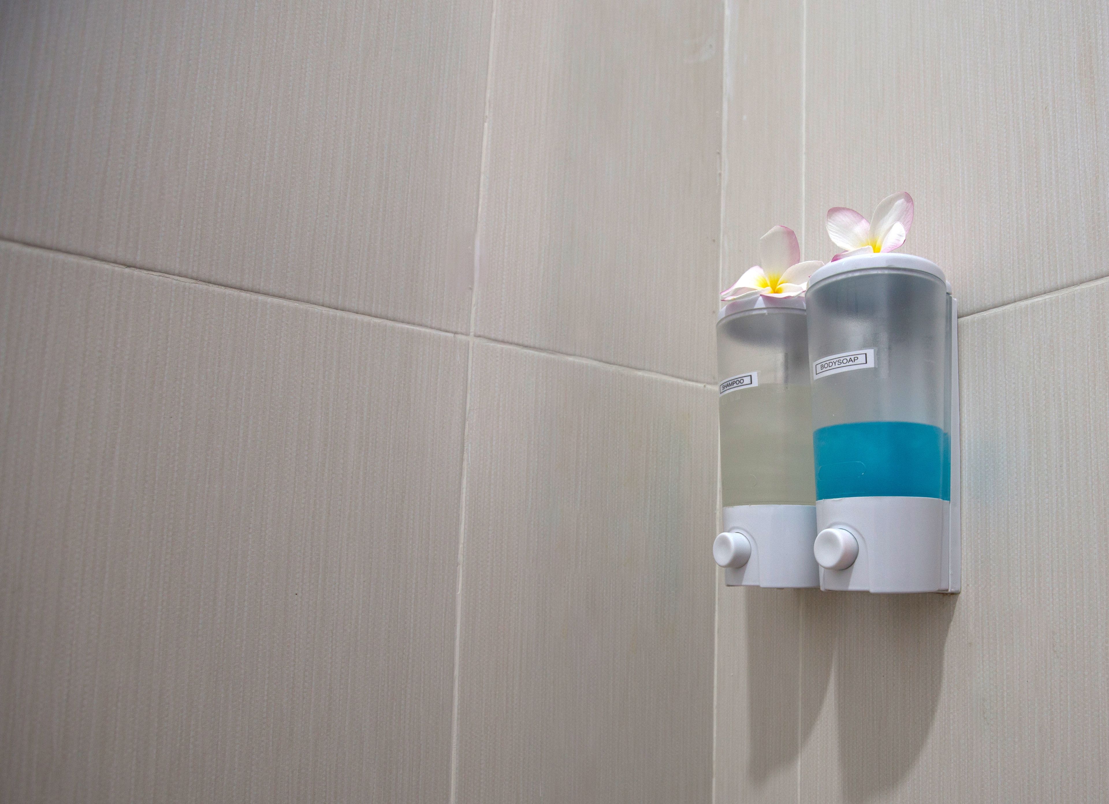 Un distributeur de savon mural orné d’une fleur sur le dessus.