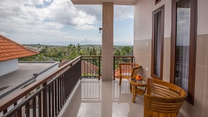 A balcony with a view of a residential area, a wooden chair, and a small table with a flower vase. - Arie Guest House Nusa Penida (Penida Island)