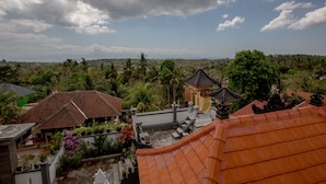 A traditional building with a tiled roof, surrounded by lush greenery and palm trees. - Arie Guest House Nusa Penida (Penida Island)