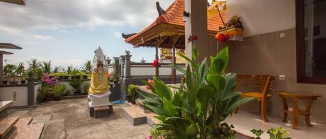 A covered outdoor area with a traditional pavilion, seating, and potted plants.