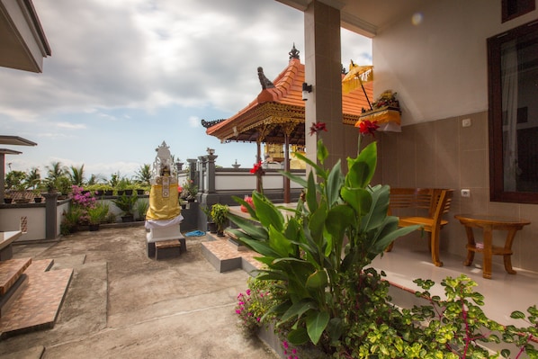 A covered outdoor area with a traditional pavilion, seating, and potted plants.