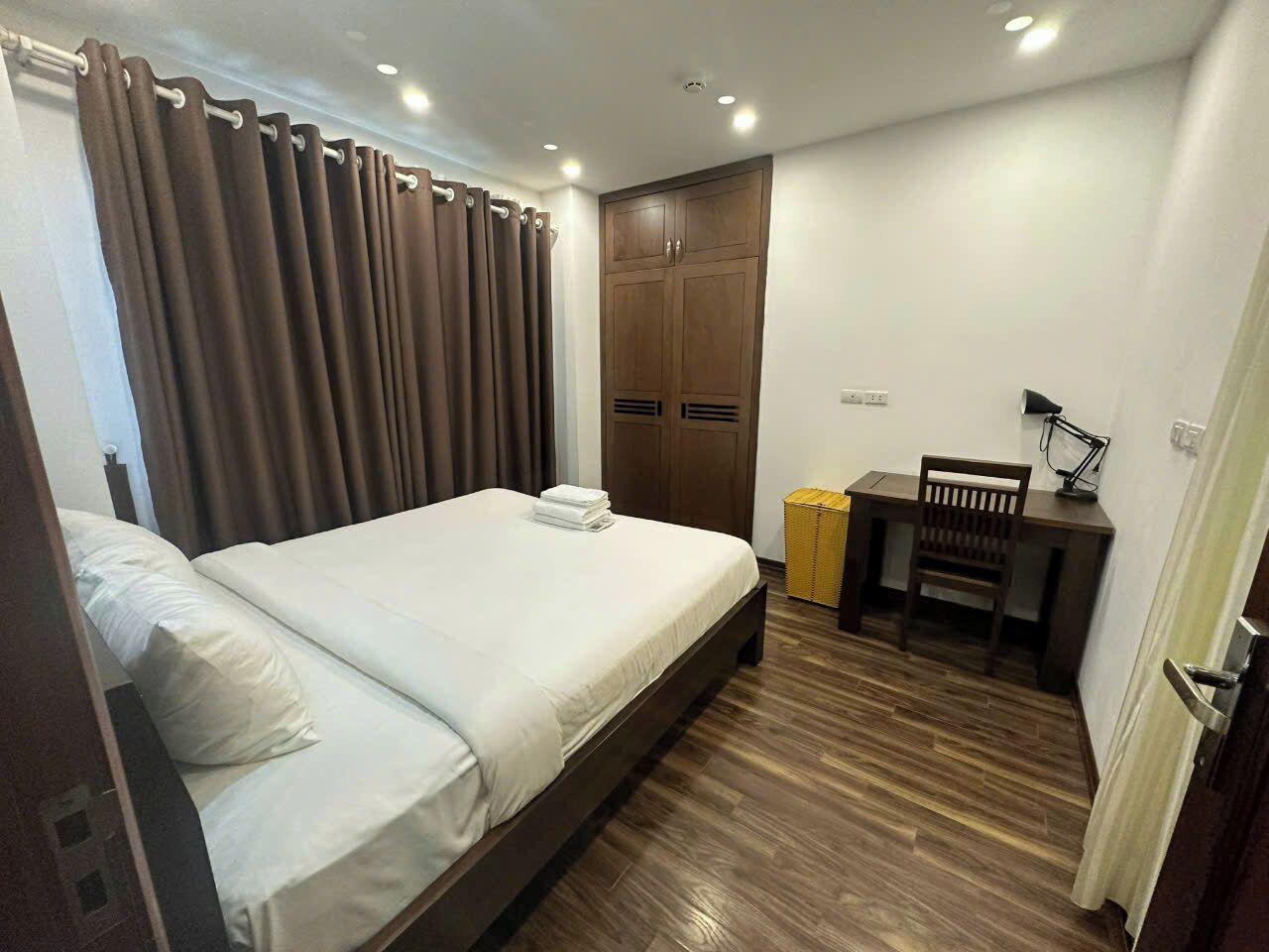 A hotel room with a bed, a desk, a chair, and a wardrobe.