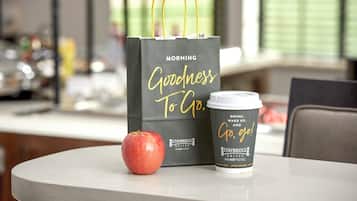A coffee cup and a black shopping bag with gold lettering on a table.