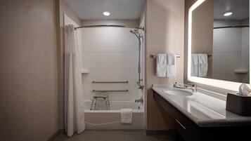 A modern bathroom with a walk-in shower, a bathtub, a vanity with a sink, and a large mirror.