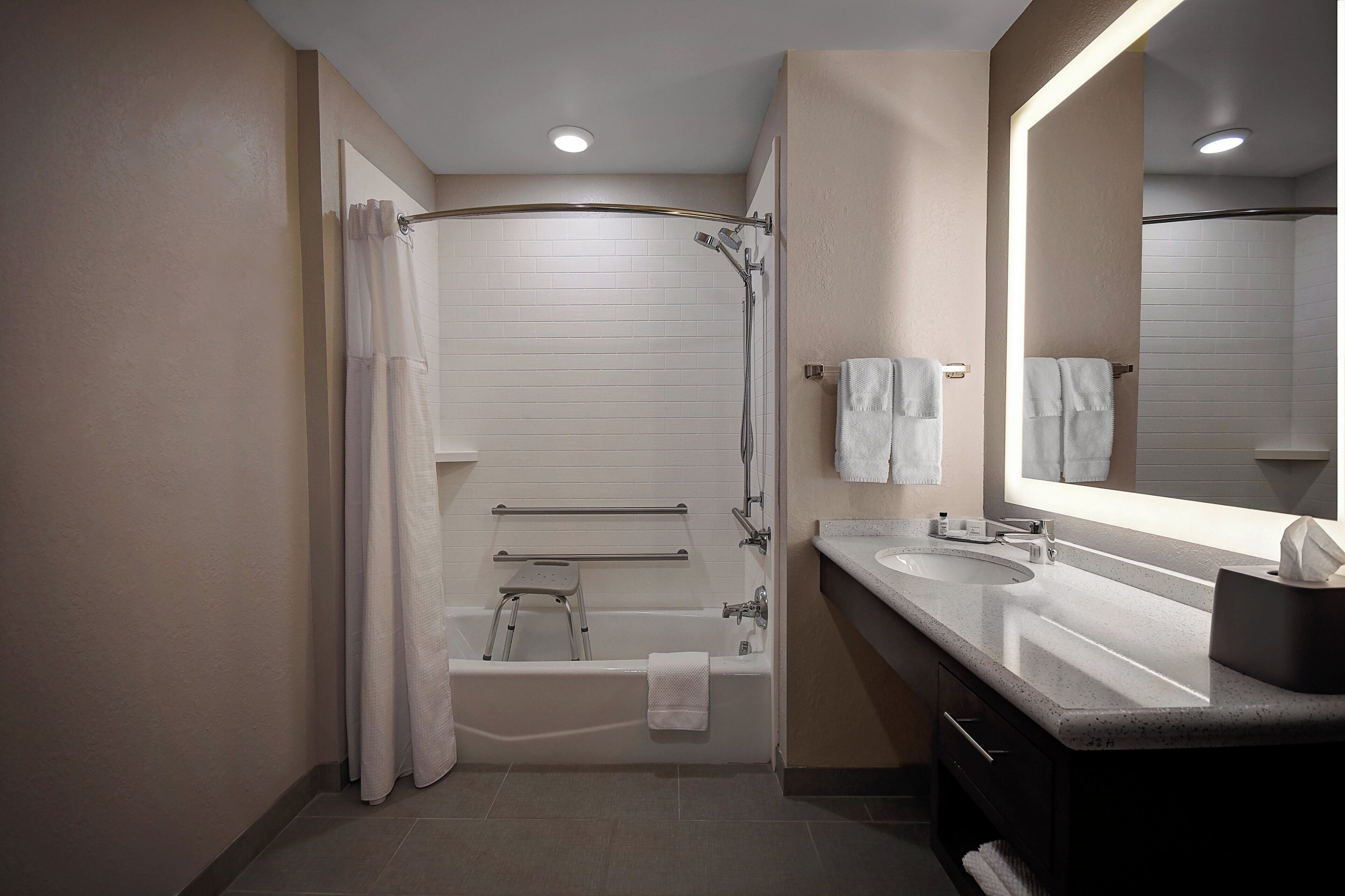 Een moderne badkamer met douche, bad en twee wastafels.