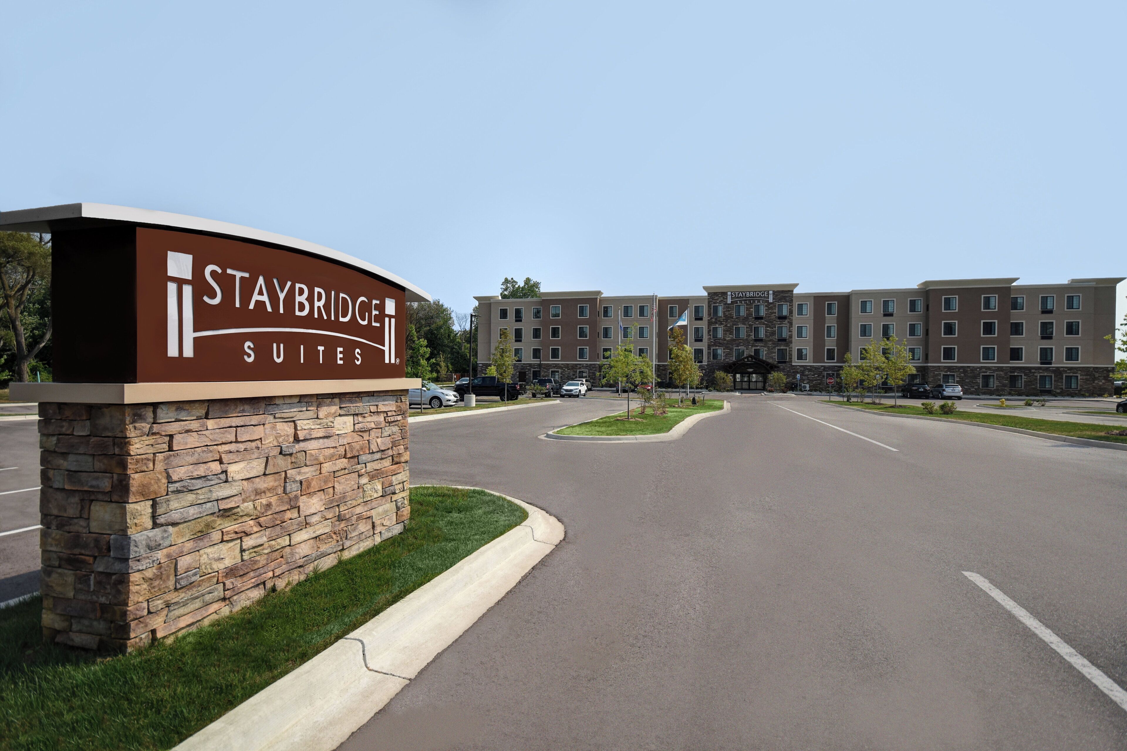 A Staybridge Suites sign with a stone base and a clear view of the hotel buildings in the background.