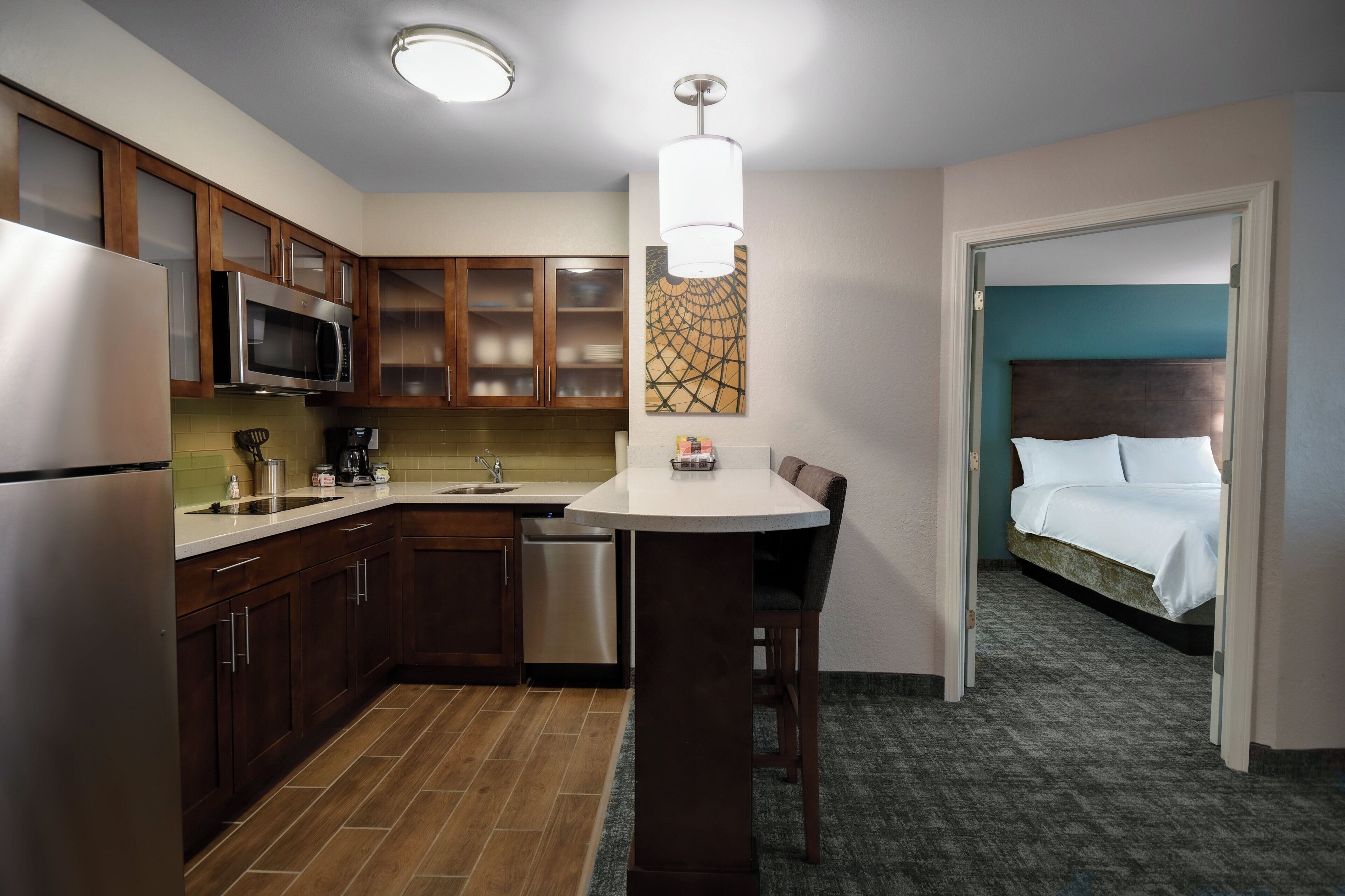 A compact hotel room with a kitchenette, a bed, and a bathroom.