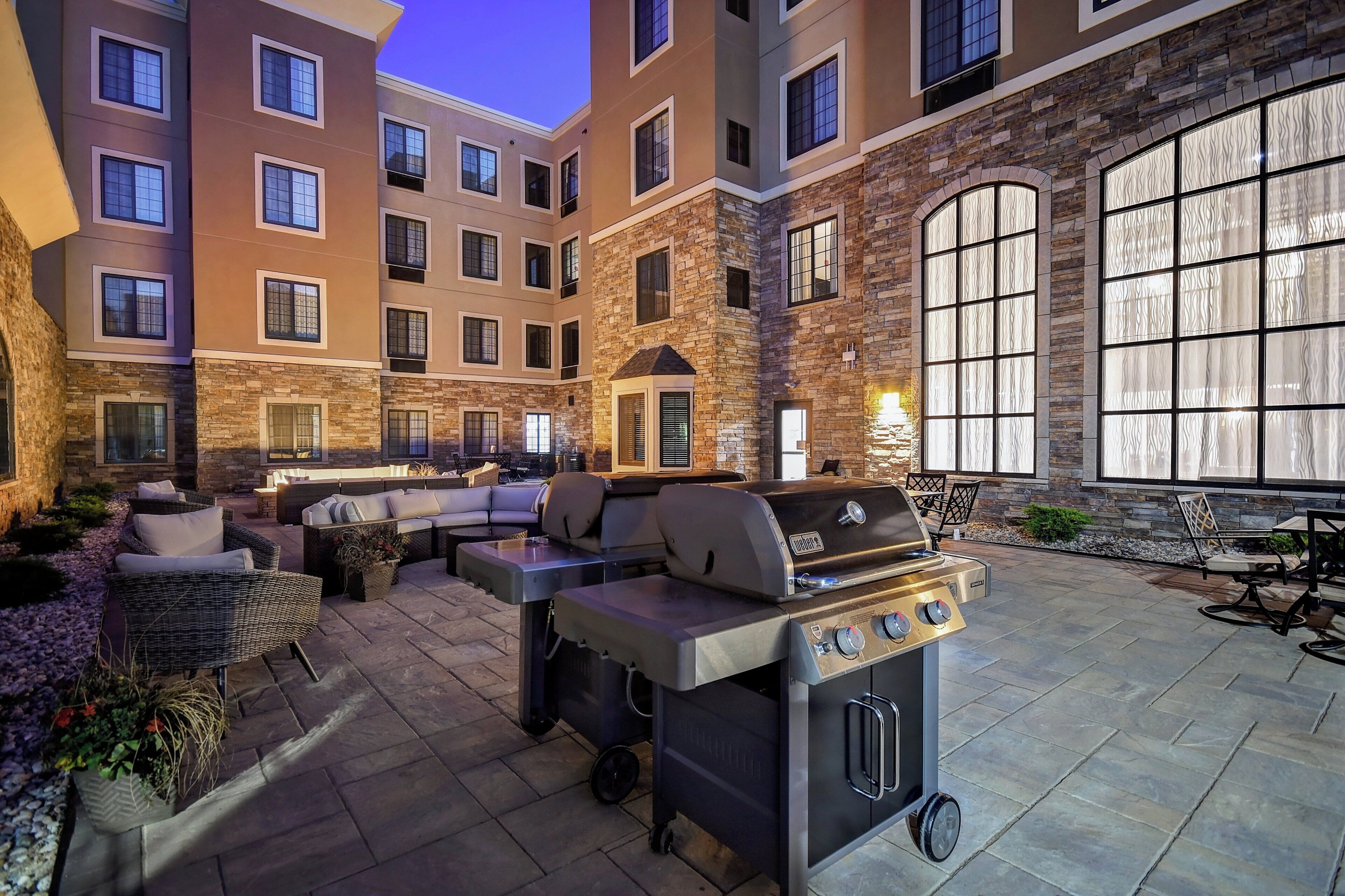 An outdoor patio with a built-in grill, seating area, and stone walls.