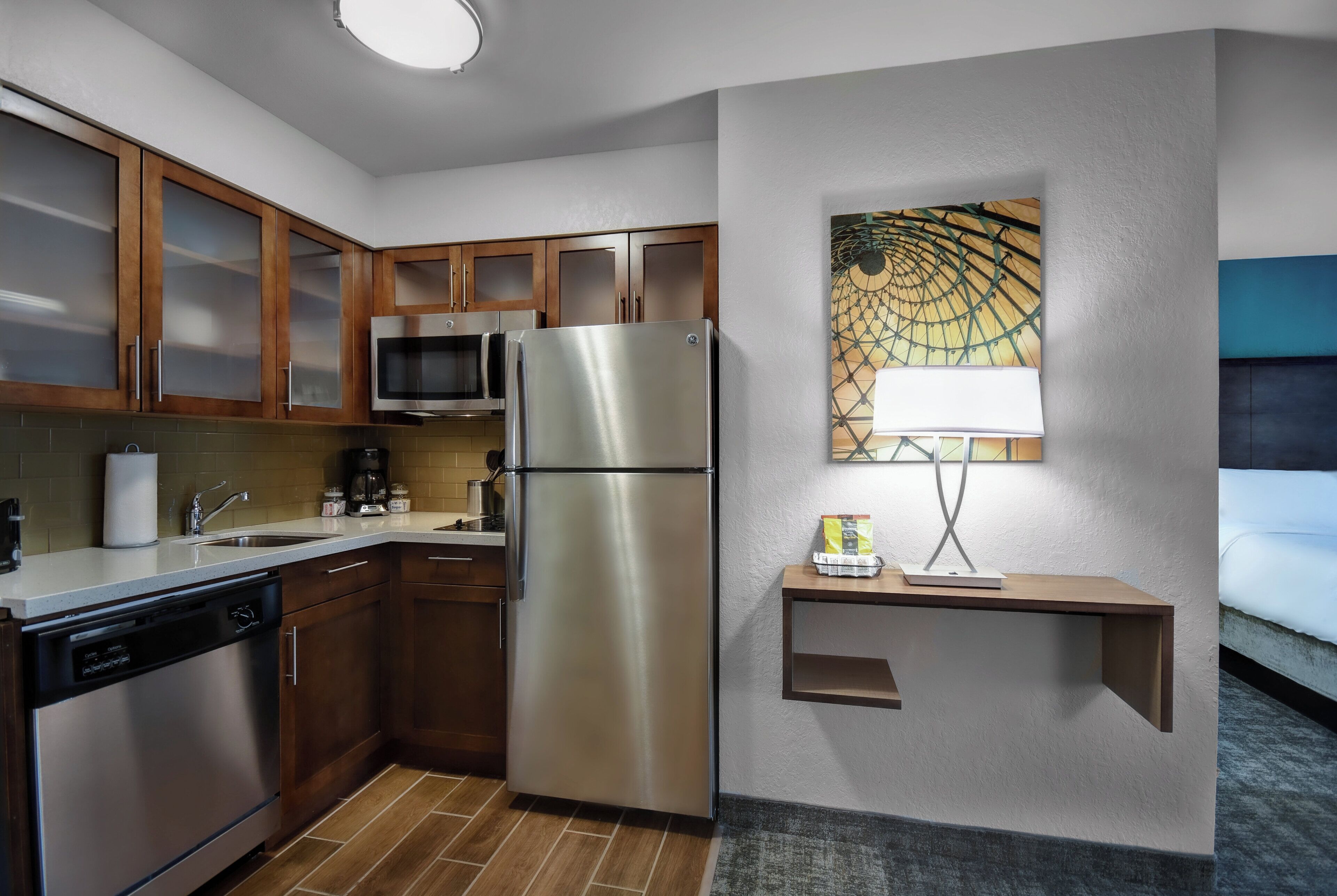 A modern kitchen with stainless steel appliances, wooden cabinets, and a microwave.