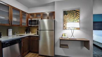 A modern kitchen with stainless steel appliances, wooden cabinets, and a microwave.