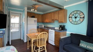 Une cuisine de taille réduite, dotée de meubles en bois, d’un réfrigérateur, d’un four à micro-ondes, d’une cuisinière et d’un ventilateur de plafond.