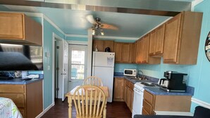 Une cuisine avec des meubles de rangement en bois, un four à micro-ondes, une cuisinière et un ventilateur de plafond.