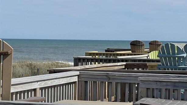 Une vue sur la plage avec des chaises longues en bois et une clôture en bois.