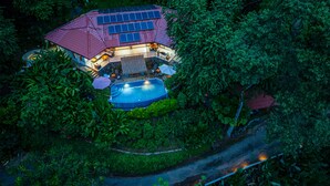 Una casa con piscina rodeada de exuberante vegetación.