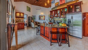 Una cocina amplia con una isla grande, armarios de madera y un refrigerador de acero inoxidable.