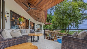 Un amplio espacio al aire libre con mobiliario de mimbre y una mesa de madera, con vistas panorámicas.