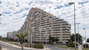 Un edificio residencial de varios pisos con fachada curva, situado cerca de una intersección.