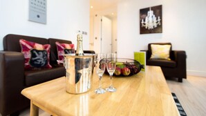 A modern living room with a wooden coffee table, a champagne bottle, and two glasses. - A modern apartment, equipped with everything for a comfortable stay (Portsmouth)