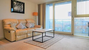 A modern living room with a reclining sofa, a coffee table, and a large window with a view of the city. - A modern apartment, equipped with everything for a comfortable stay (Portsmouth)