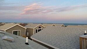 A row of beach cottages with pitched roofs and a view of the ocean.