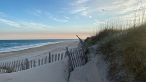 A beach with a wooden fence and dunes.