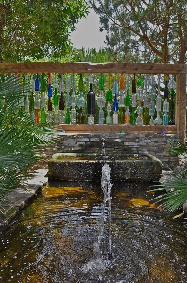 A garden with a water feature and a wall of hanging glass bottles. - Casa de Gertrudis - Traditional Spanish house , just 200m from sandy beach (El Palmar de Vejer)