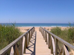 A wooden boardwalk leading to a beach with clear skies. - Casa de Gertrudis - Traditional Spanish house , just 200m from sandy beach (El Palmar de Vejer)