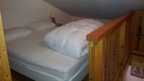 A small, single-bed room with a wooden headboard and a nightstand with a lamp. - Cozy Duplex for 5, Close to Ski Lifts & Shops, South-Facing Balcony – Alpe d'Huez (Huez)