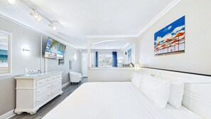 Une chambre d’hôtel avec un grand lit, une commode, une coiffeuse et un tableau au mur.