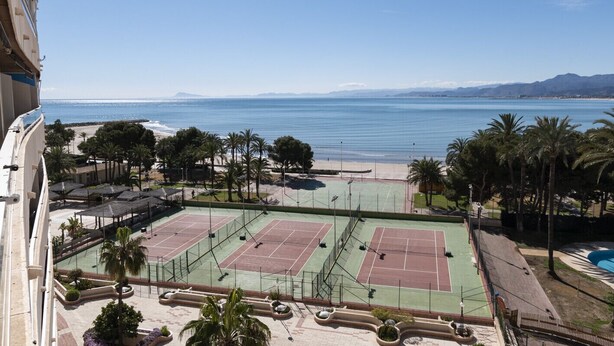 Complejo de canchas de tenis con vista a la playa y al océano.