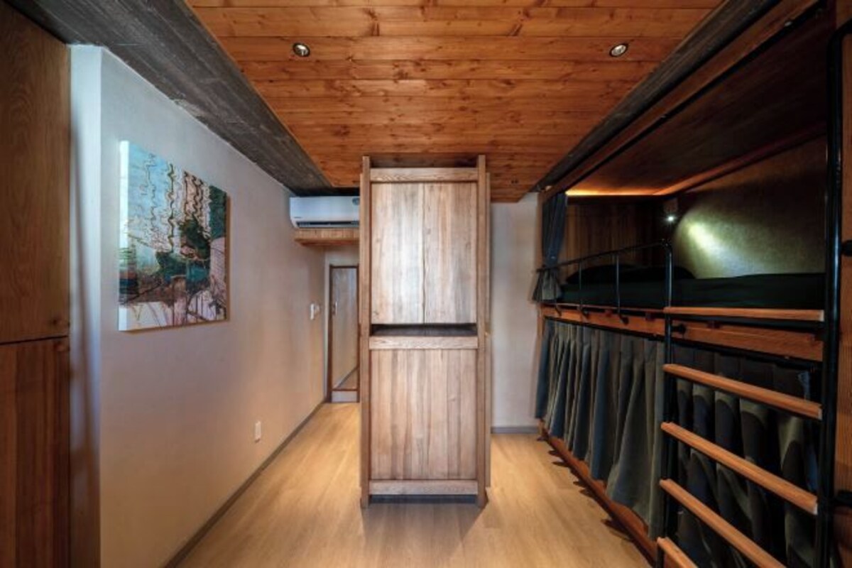 Een gang met houten vloer, houten plafond en een schuifdeur.