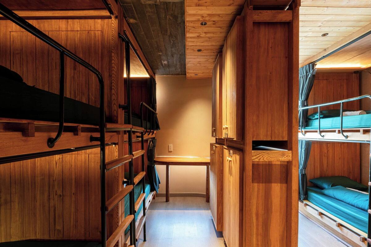 A narrow hallway with bunk beds on both sides, wooden walls, and a wooden ceiling.