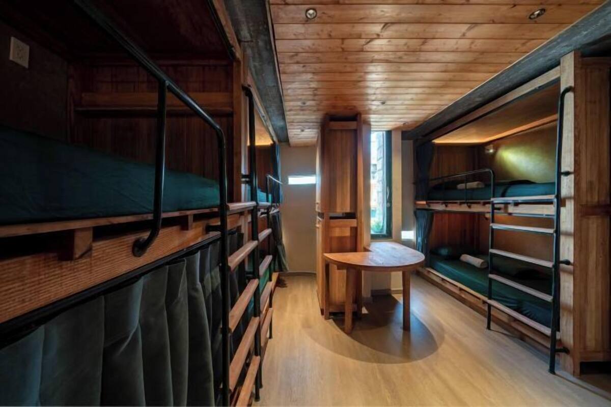 A cabin with bunk beds, a small table, and a window.