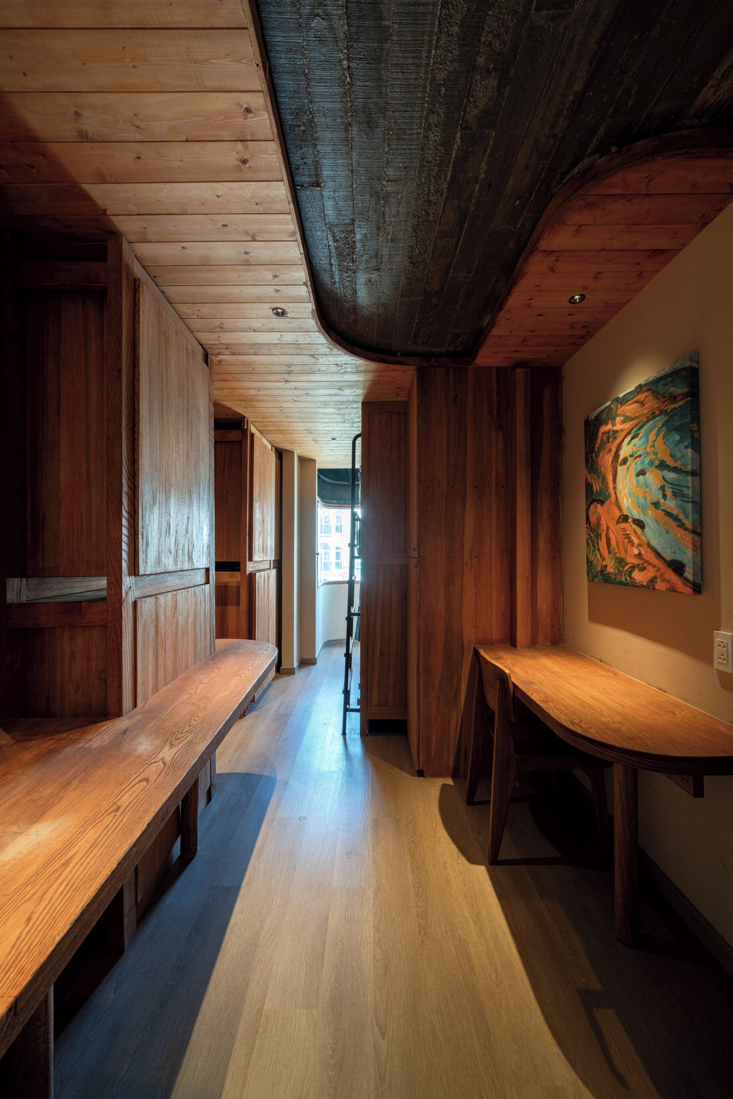 A hallway with wooden benches and a painting on the wall.
