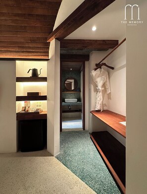 A narrow hallway with a wooden bench, a robe hanging on a rack, and a small shelf with a kettle. - The Memory Danang Boutique (Da Nang)
