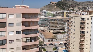 A multi-story residential building with balconies, a parking area, and a view of a hill with a structure on top. - LIDER, 12-A (Cullera)