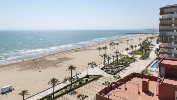 A beach view from a hotel balcony with a pool, palm trees, and a clear sky. - LIDER, 12-A (Cullera)