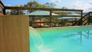 A pool with a wooden deck and a view of the surrounding area. - Rural house surrounded by mountains with swimming pool, skatepark and children's playground in Llerena (Ribera de los Molinos, Llerena)